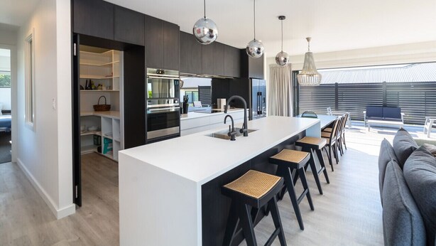 A modern kitchen with a central island, bar stools, and pendant lighting. - Vinebox On Wilson, Martinborough (Martinborough)