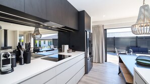 A modern kitchen with a large island, built-in appliances, and a dining area with a view. - Vinebox On Wilson, Martinborough (Martinborough)