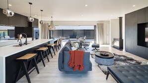 A modern kitchen with a central island, bar stools, and a seating area with a sofa and ottoman. - Vinebox On Wilson, Martinborough (Martinborough)