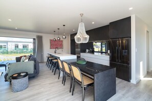A modern kitchen with a central island, bar stools, and a large refrigerator. - Vinebox on Wilson, Martinborough (Martinborough)