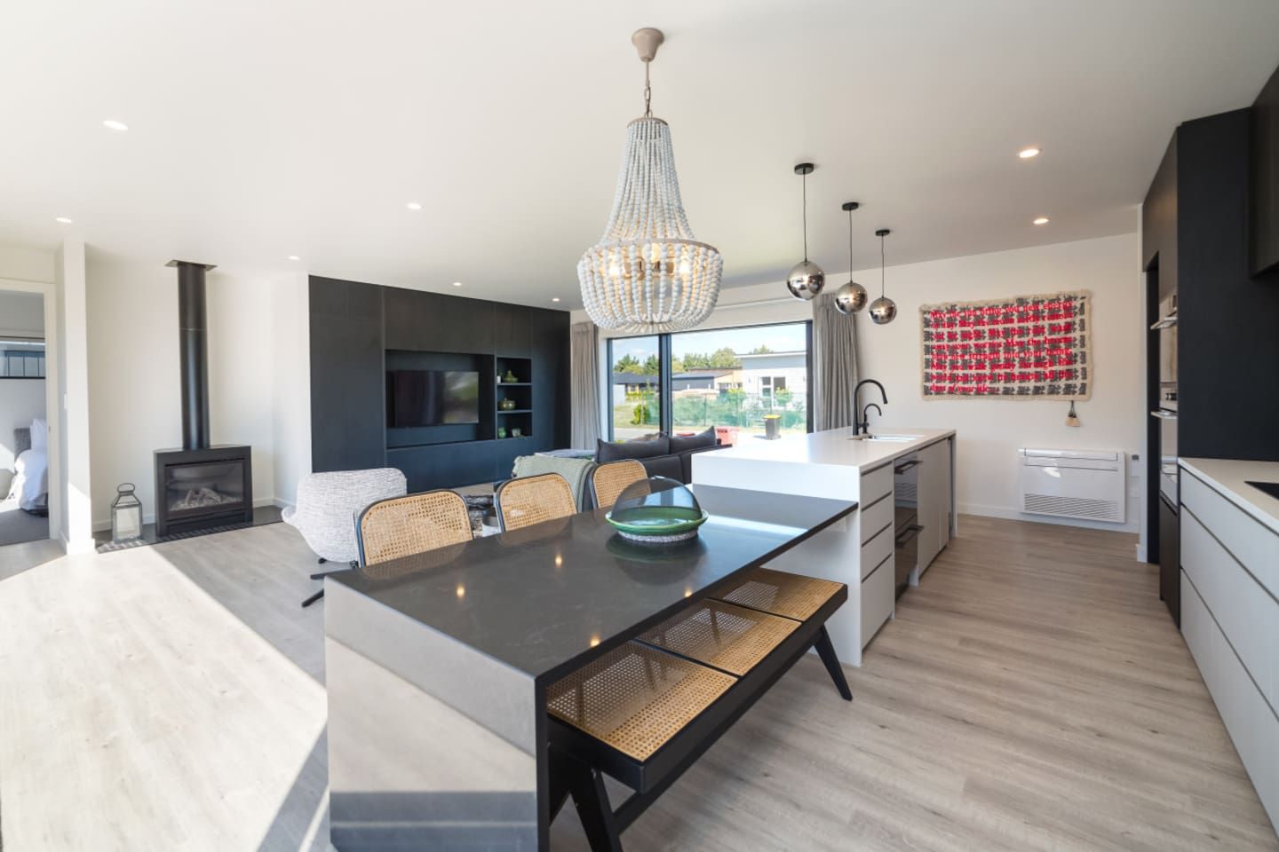 A modern kitchen with a central island, pendant lighting, and a view to the outdoors.