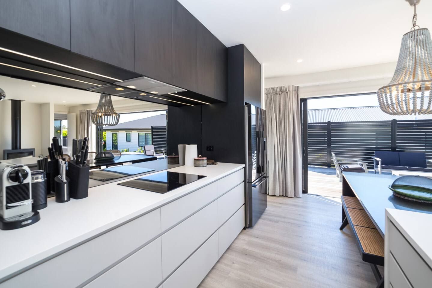 Une cuisine moderne dotée d’un îlot central, d’appareils électroménagers intégrés et d’un coin repas avec espace extérieur aménagé.