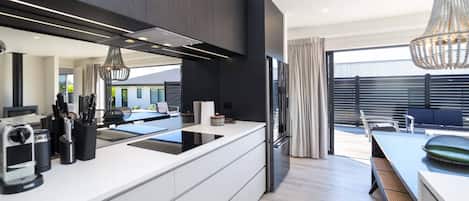 A modern kitchen with a central island, built-in appliances, and a dining area with outdoor seating.