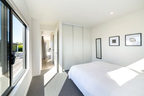 A hotel room with a large bed, a sliding door closet, and a view of the outside. - Vinebox on Wilson, Martinborough (Martinborough)