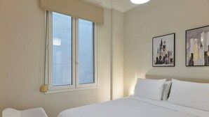 Ein Hotelzimmer mit einem großen Bett, einem Sessel und zwei Stadtansichten an der Wand.