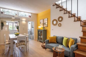A modern living room with a staircase, a dining area, and a view of the outside.