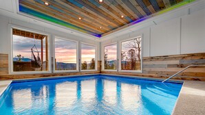 An indoor swimming pool with wooden walls and large windows.