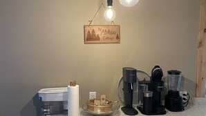 Una cocina con encimera de mármol, cafetera, licuadora e iluminación colgante.