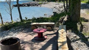 Un área de picnic con un banco de madera, una mesa roja y un hogar para fuego.