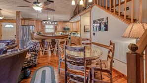A spacious kitchen with wooden cabinets, a central island, and a dining area with a glass table.