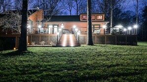 A modern building with a wooden exterior, a covered outdoor area with seating, and a staircase leading to a deck.
