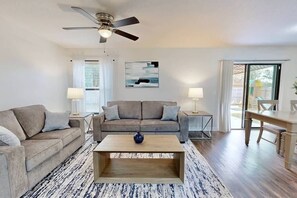 Uma sala de estar moderna com sofá, mesa de centro e ventilador de teto.