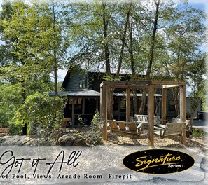 A cabin with a wooden deck, a swing set, and a view of the surrounding forest. - Tennessee Treasure 11 Beds Pool Theater (Sevierville)