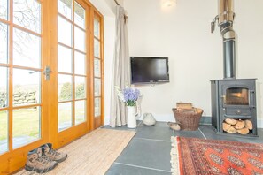 A living room with a stone fireplace, a television, and a large window with a view of the outdoors.