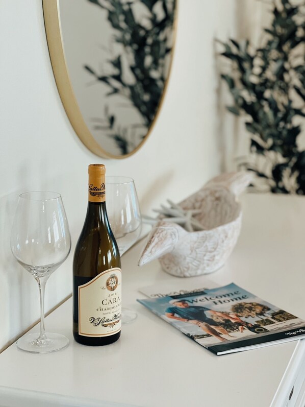 A bottle of wine, two glasses, and a magazine on a white surface.