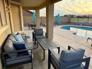 An outdoor patio with a pool, seating area, and umbrellas. - 5BR/3BA Home with Private Heated Pool and Golf Course Views in San Tan Valley (San Tan Valley)