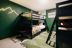 Habitación con literas, una pared verde, un cartel que dice 'COOL KIDS CLUB' y una alfombra a rayas.