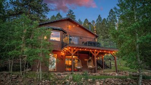 A cabin with a balcony, hanging chairs, and a porch with string lights. - NEW Hot Tub + Arcade + Fire Pit + Mtn Views (Bailey)