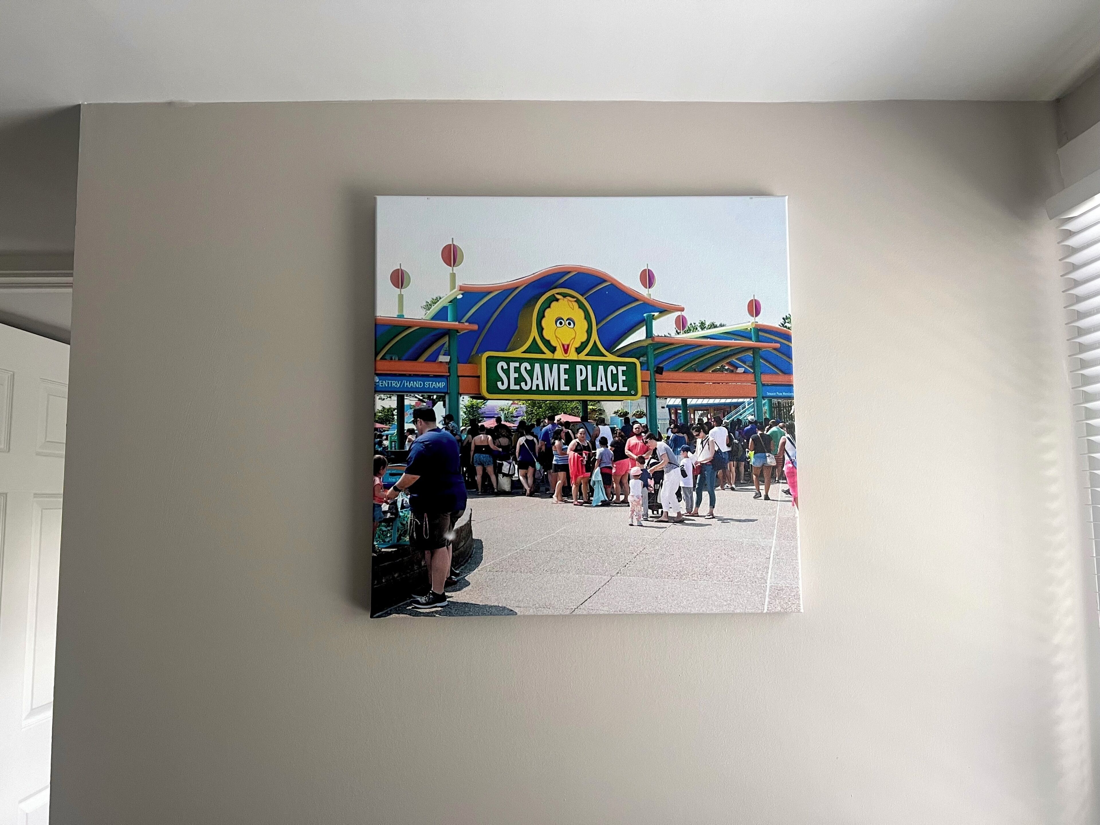 A wall-mounted painting of Sesame Place entrance with a crowd.