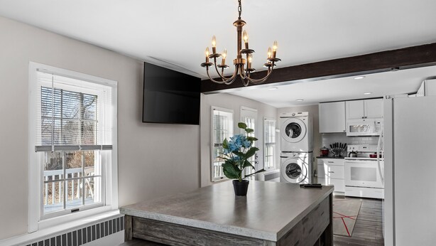 A modern kitchen with a central island, built-in appliances, and a large window with blinds.