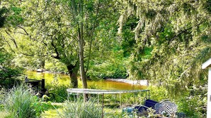 A garden with a pond, a wooden bench, raised garden beds, and various plants.