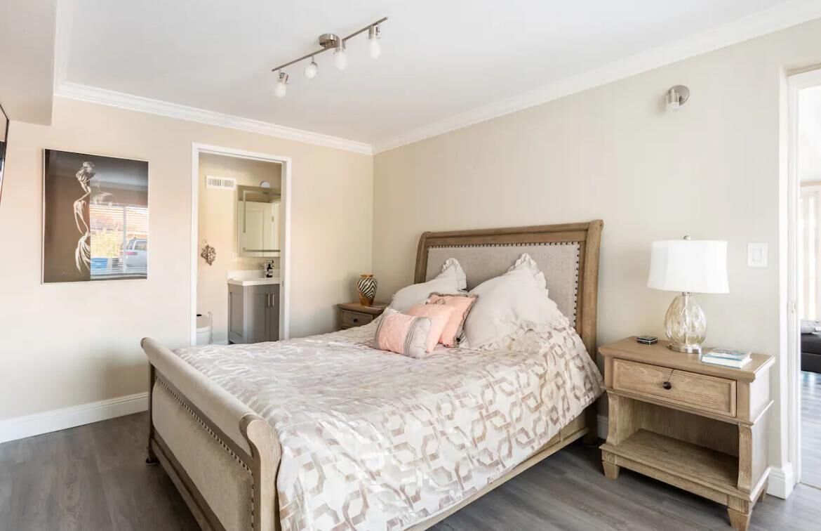 Une chambre à coucher comprenant un lit, des tables de chevet, une commode, un miroir et un luminaire fixé au mur.