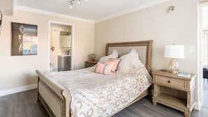 Quarto com cama, mesas de cabeceira, um espelho e luminária na parede.
