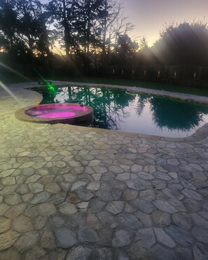 Una piscina amb terrassa de pedra i zona de banyera d'hidromassatge.