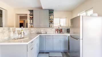 Une cuisine moderne avec des meubles gris, un réfrigérateur blanc et un plan de travail en marbre.