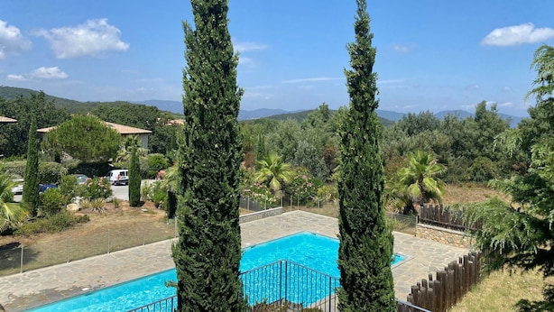 A pool area with tall trees, a stone deck, and a view of distant hills. - Splendide Appartement Dans Résidence Sécurisée Avec Piscine Proche du Village (La Croix-Valmer)