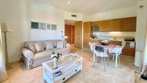A living room with a sofa, coffee table, and a dining area with chairs and a table. - Splendide Appartement Dans Résidence Sécurisée Avec Piscine Proche du Village (La Croix-Valmer)