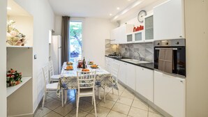 Une cuisine compacte avec des meubles blancs, un four encastré et un coin repas avec une table dressée pour quatre personnes.