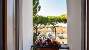 Un balcon agrémenté de plantes en pot, avec vue sur un parking et des arbres.