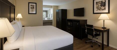 Habitación de hotel con una cama grande, un escritorio con silla, televisión y un cuadro en la pared.
