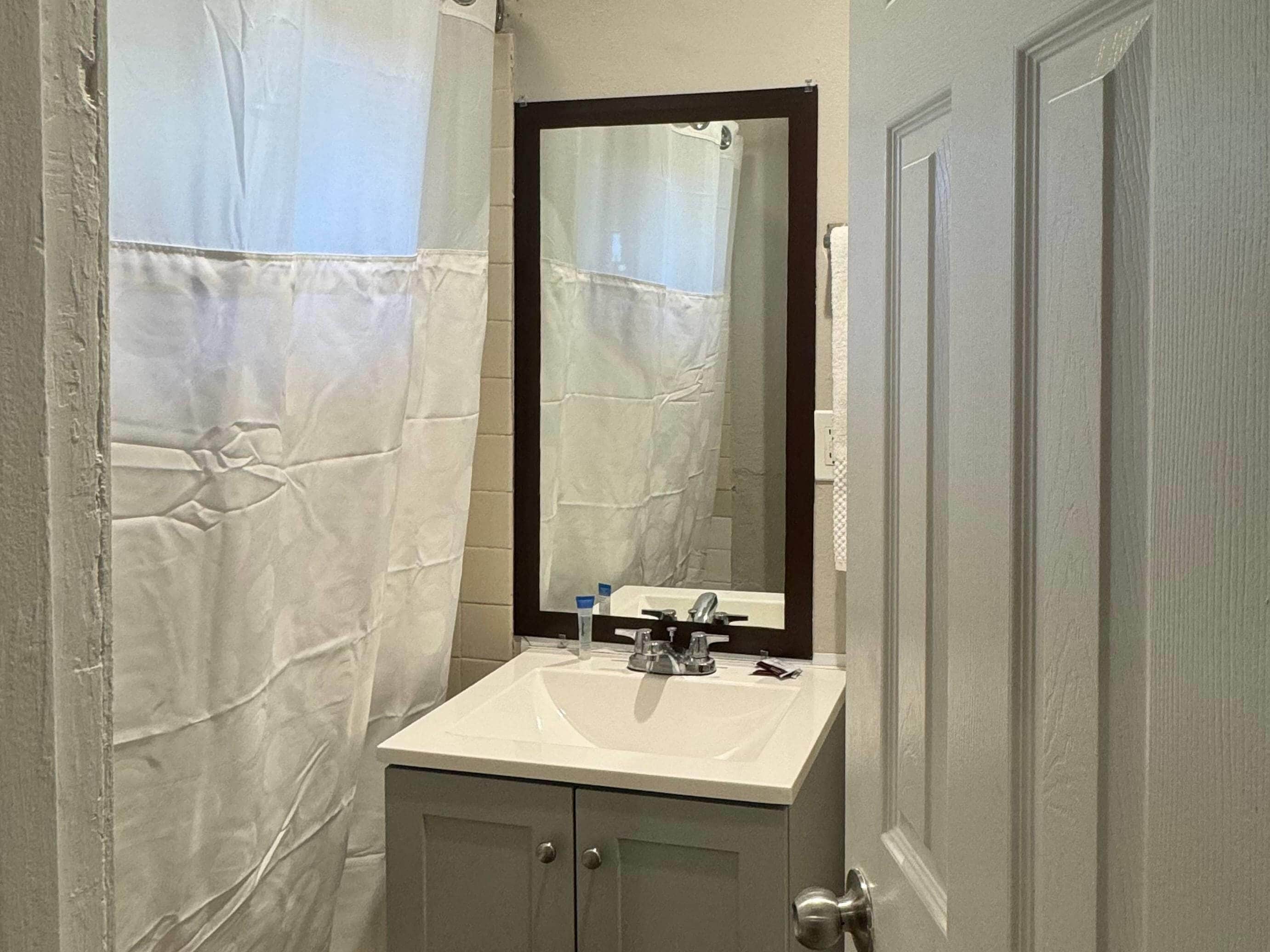 A bathroom with a white sink, a mirror, and a shower curtain.