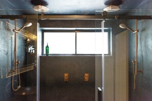 Een moderne badkamer met een glazen douchecabine, een raam en twee douchekoppen.