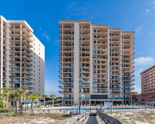 A high-rise hotel with multiple balconies, a swimming pool, and a boardwalk leading to the pool. - Beach Front Condo - View of Perdido Pass - See Description for Discount Dates!! (Orange Beach)