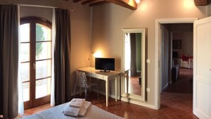 Un dormitorio con una cama, un escritorio con computadora y una ventana con cortinas.