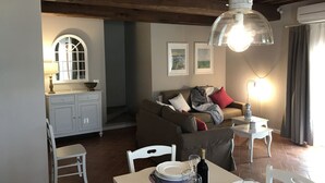 Una sala de estar acogedora con una mesa de comedor lista para dos personas, un sofá y una ventana con vistas.