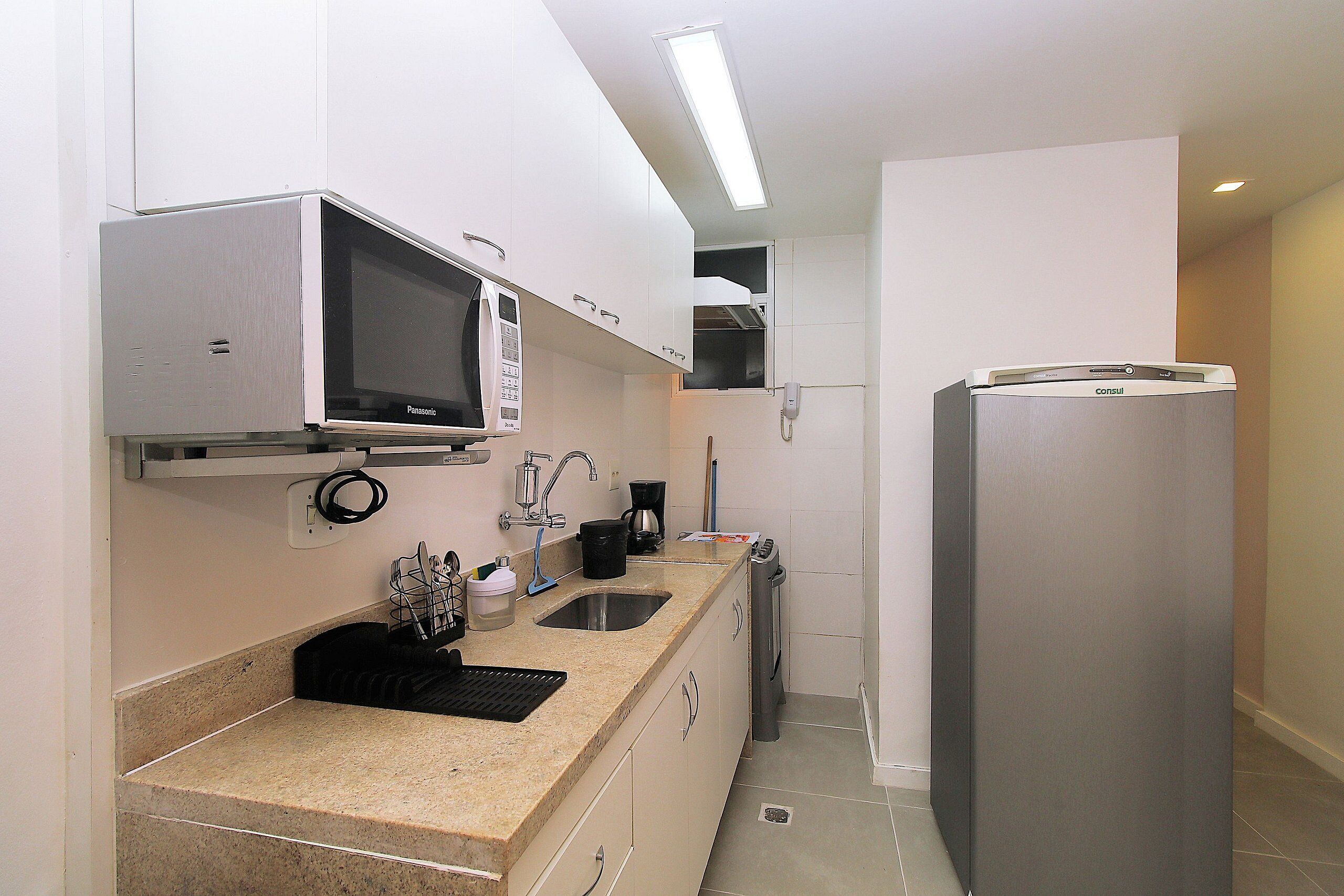 Una cocina compacta con microondas, cafetera y refrigerador.
