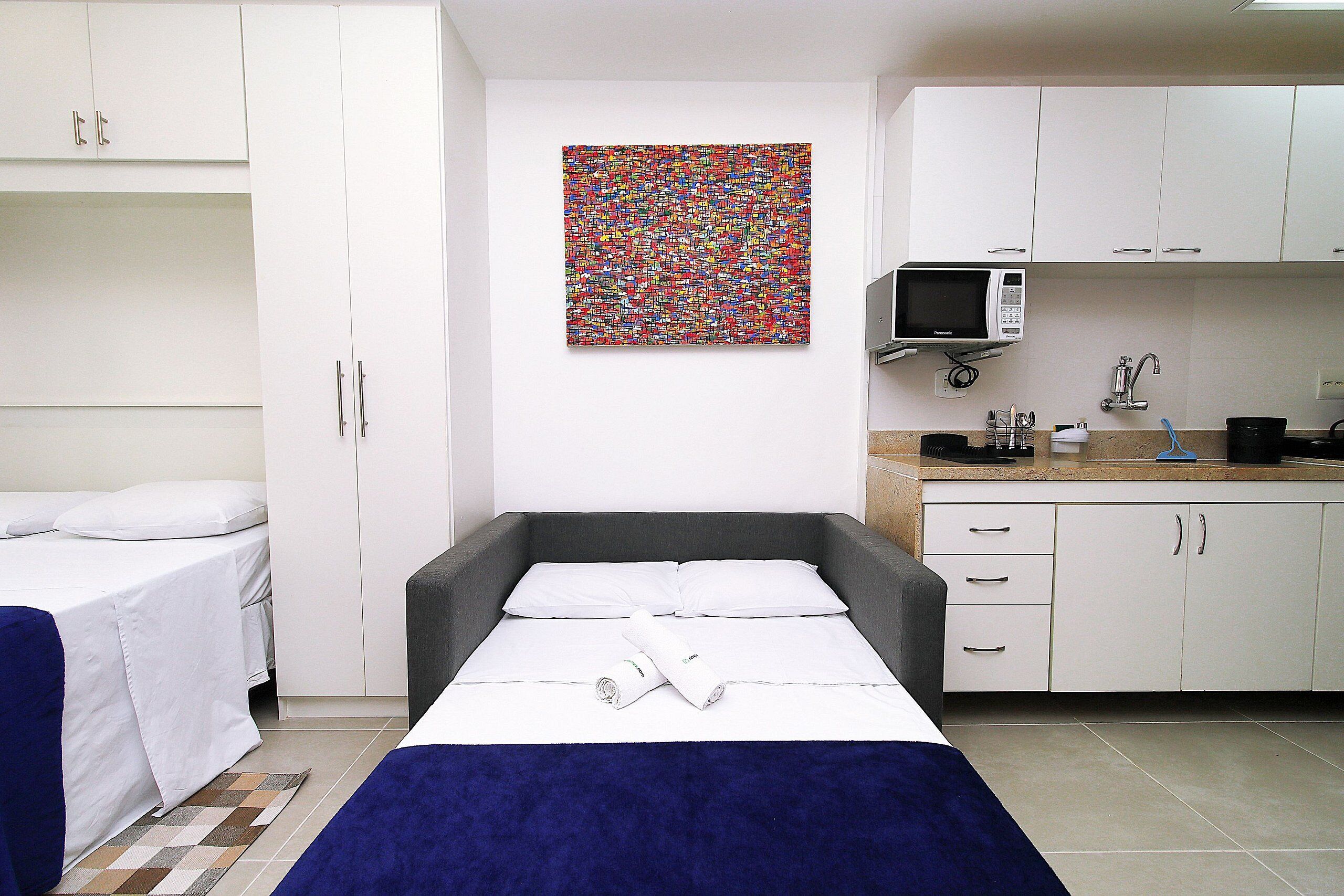 Una stanza con un letto, una scrivania, un forno a microonde e un lavandino.