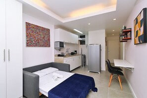 A compact room with a bed, a desk, a chair, a kitchenette, and a bathroom. - Rio Spot Homes Copacabana C059 (Rio de Janeiro)