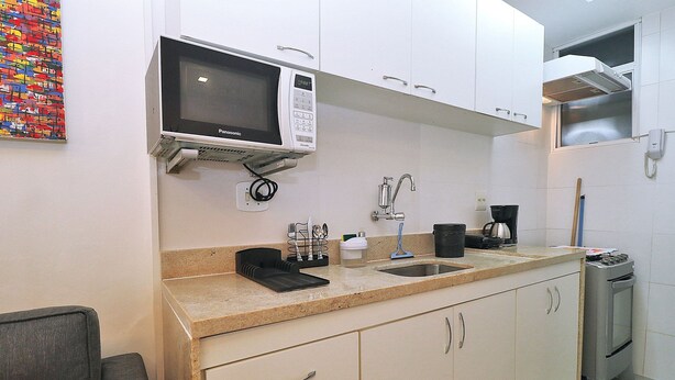 A compact kitchen with a microwave, sink, and a small oven. - Rio Spot Homes Copacabana C059 (Rio de Janeiro)