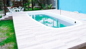 A rectangular swimming pool with a wooden deck surrounding it. - Pousada Costa Azul (Maraú)
