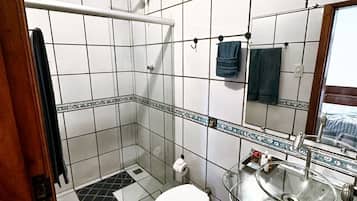 Casa de banho com chuveiro, sanita e lavatório.