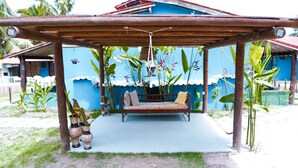 A covered outdoor seating area with a bench and potted plants. - Pousada Costa Azul (Maraú)