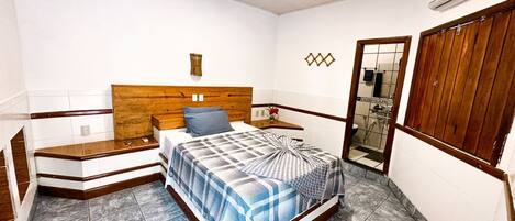 A bedroom with a wooden headboard, a bed with a blue and white checkered bedspread, a nightstand, and a mirror.