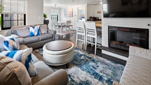 Un salon moderne avec un canapé, un pouf et une cheminée.