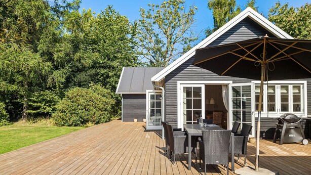 Een houten terras met tuinmeubilair, een barbecue en een overdekte patio.