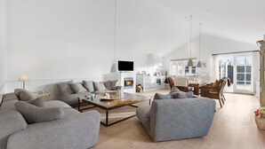 Een ruime woonkamer met een open haard, een eethoek en een keuken.